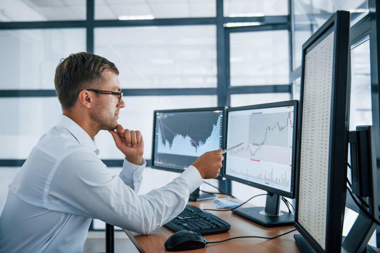 Mann an Computer mit Charts auf Monitoren