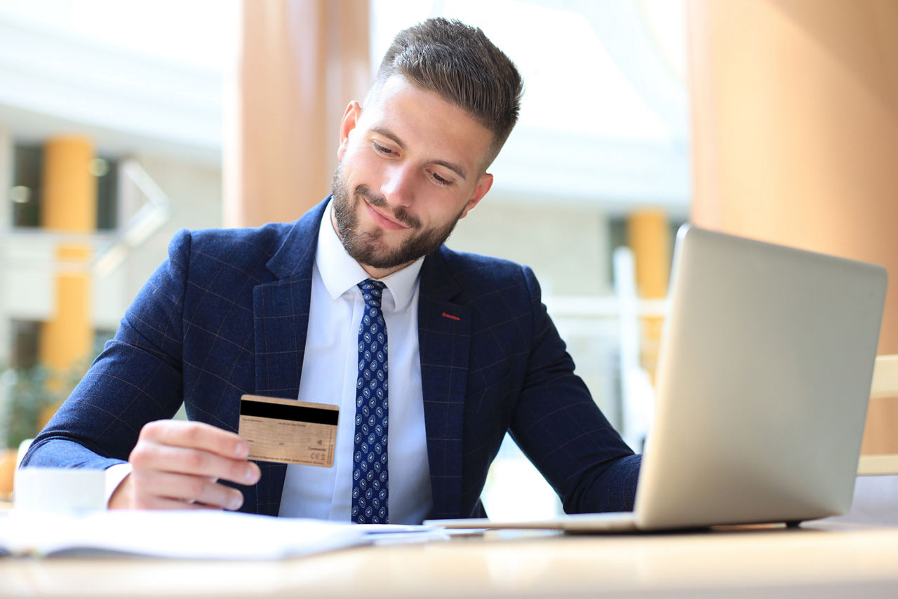 Geschäftsmann am Schreibtisch mit BusinessCard in der Hand