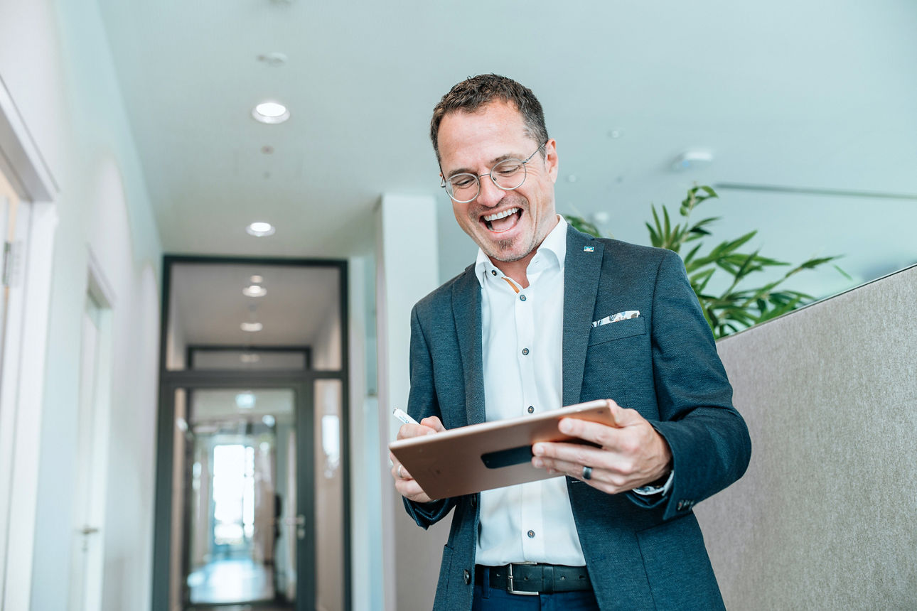 mann-mit-tablet-in-der-hand-lacht