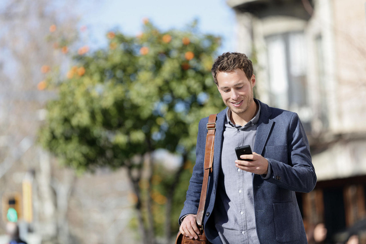 Mann unterwegs in Stadt mit Blick auf Smartphone