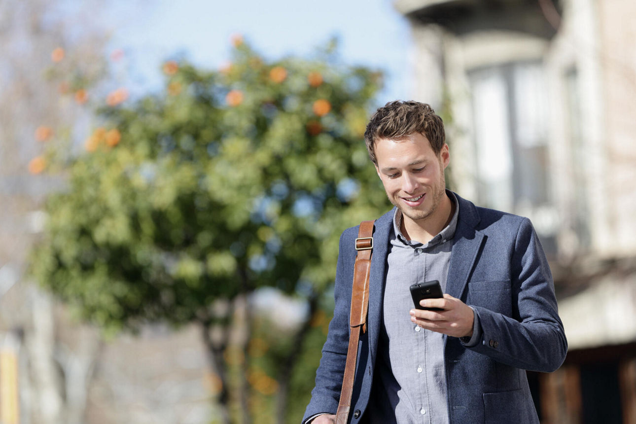 Mann unterwegs in Stadt mit Blick auf Smartphone