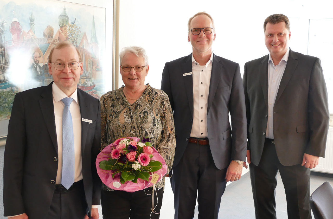 Martina Hölck hält ihren Blumenstrauß in den Händen und steht neben den Vorstandsmitgliedern sowie Betriebsratvorsitzenden