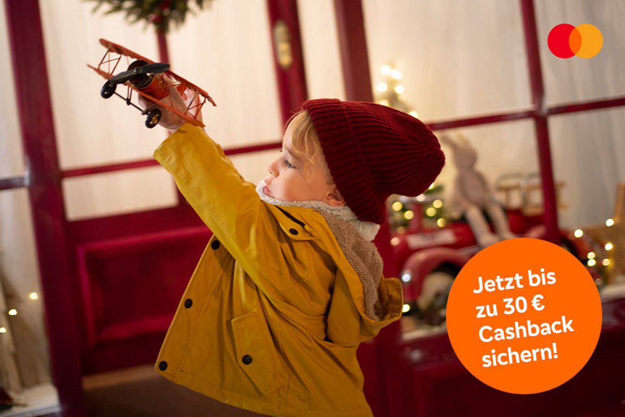 Ein kleiner Junge mit roter Mütze spielt mit seinem Modelflieger.