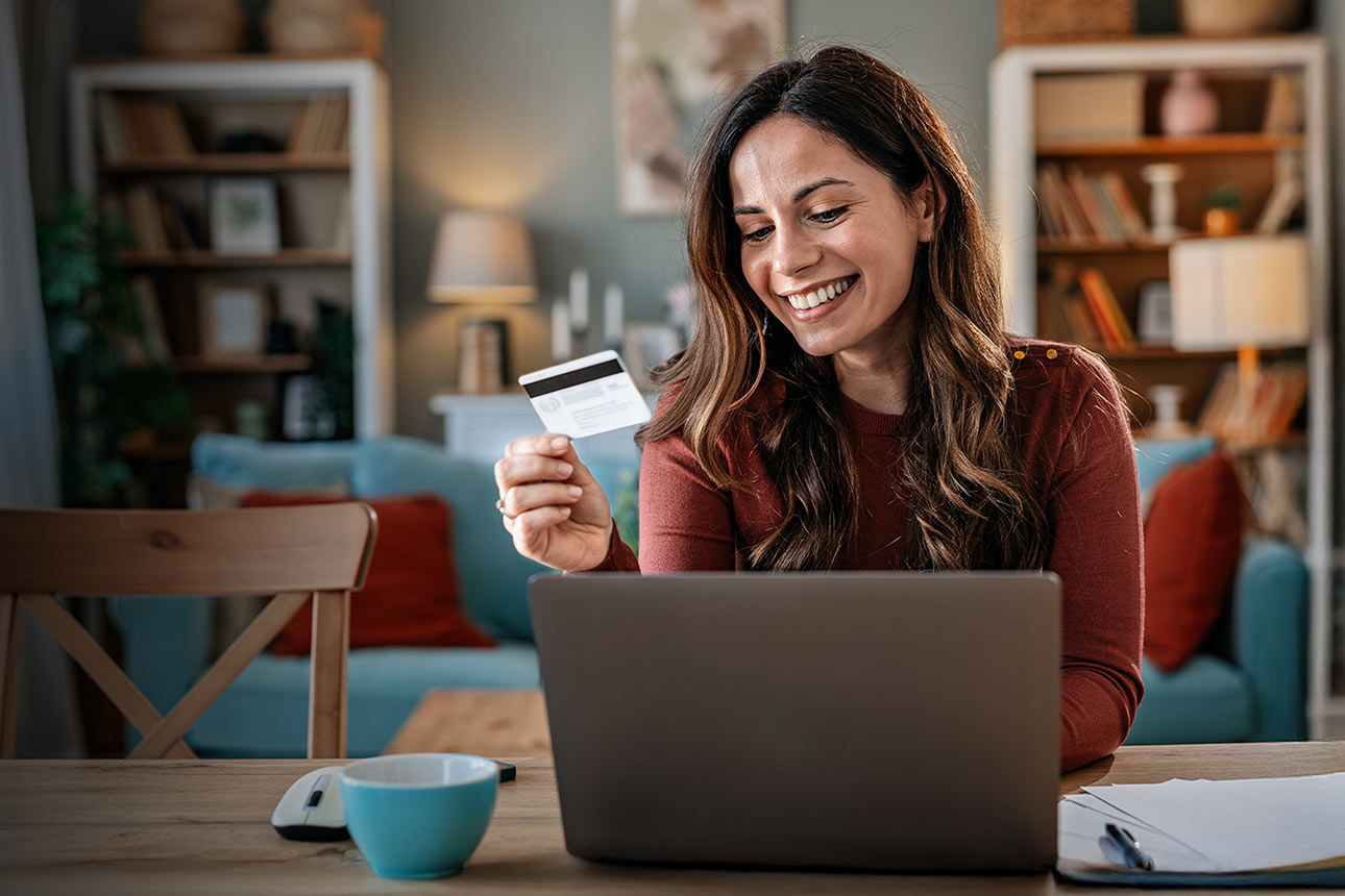 Frau mit Kreditkarte in der Hand sitz vor Laptop. Text im Bild: Deine 25 €-Cashback-Karte - Mit Mastercard online zahlen 