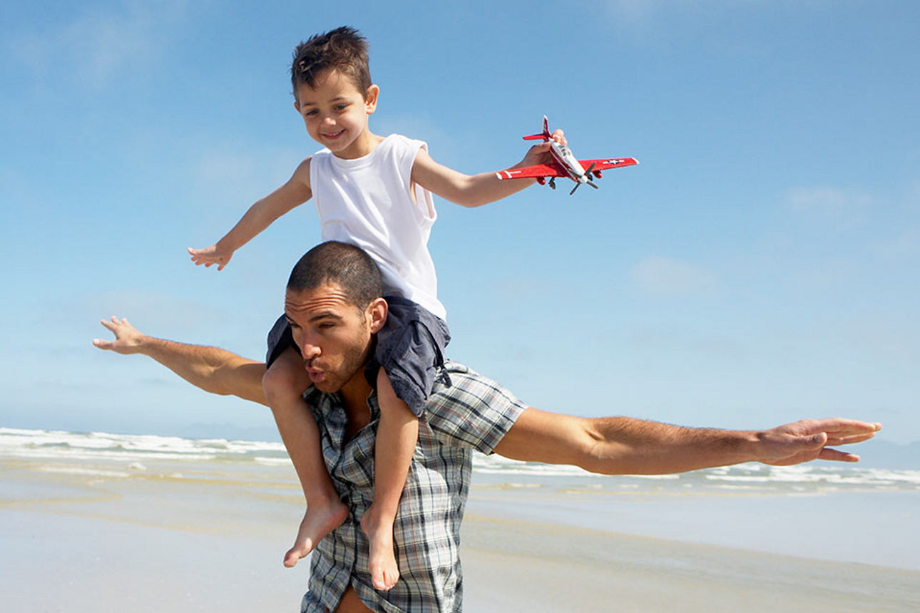Vater mit Sohn auf den Schultern am Strand