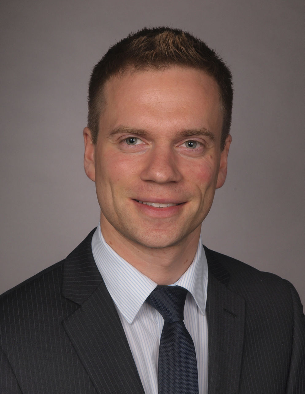 Mitarbeiter der Bank im Anzug mit dunkelblauer Krawatte lächelt in die Kamera.