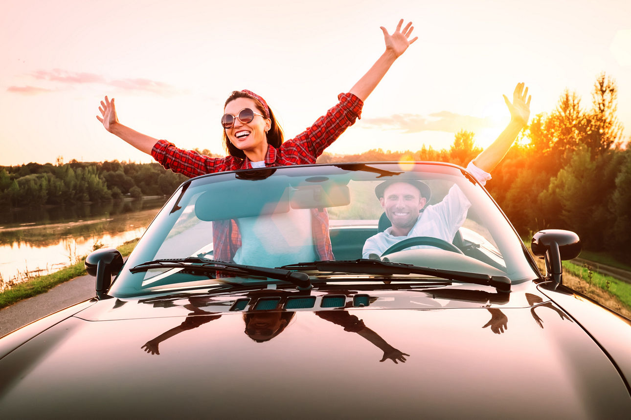 Pärchen fährt im Cabrio im Sonnenuntergang