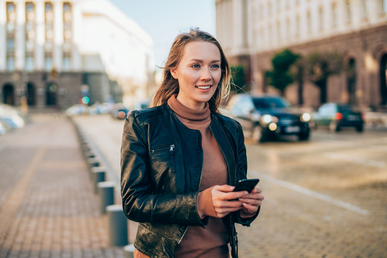Junge Frau auf der Strasse tippt in ihr Smartphone. Junge Frau auf der Strasse tippt in ihr Smartphone.