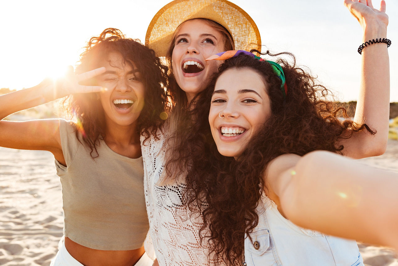 Drei junge Mädchen machen Selfies am Strand 