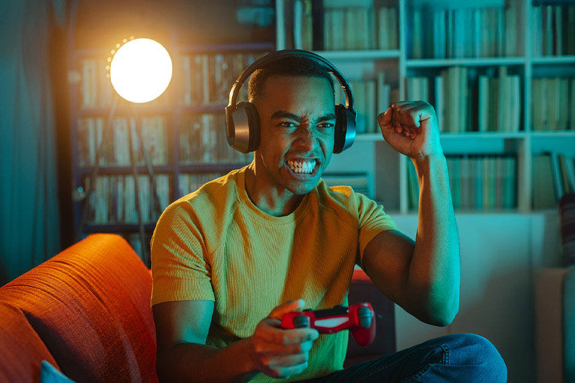Junger Mann jubelt beim Spielen an der Console.