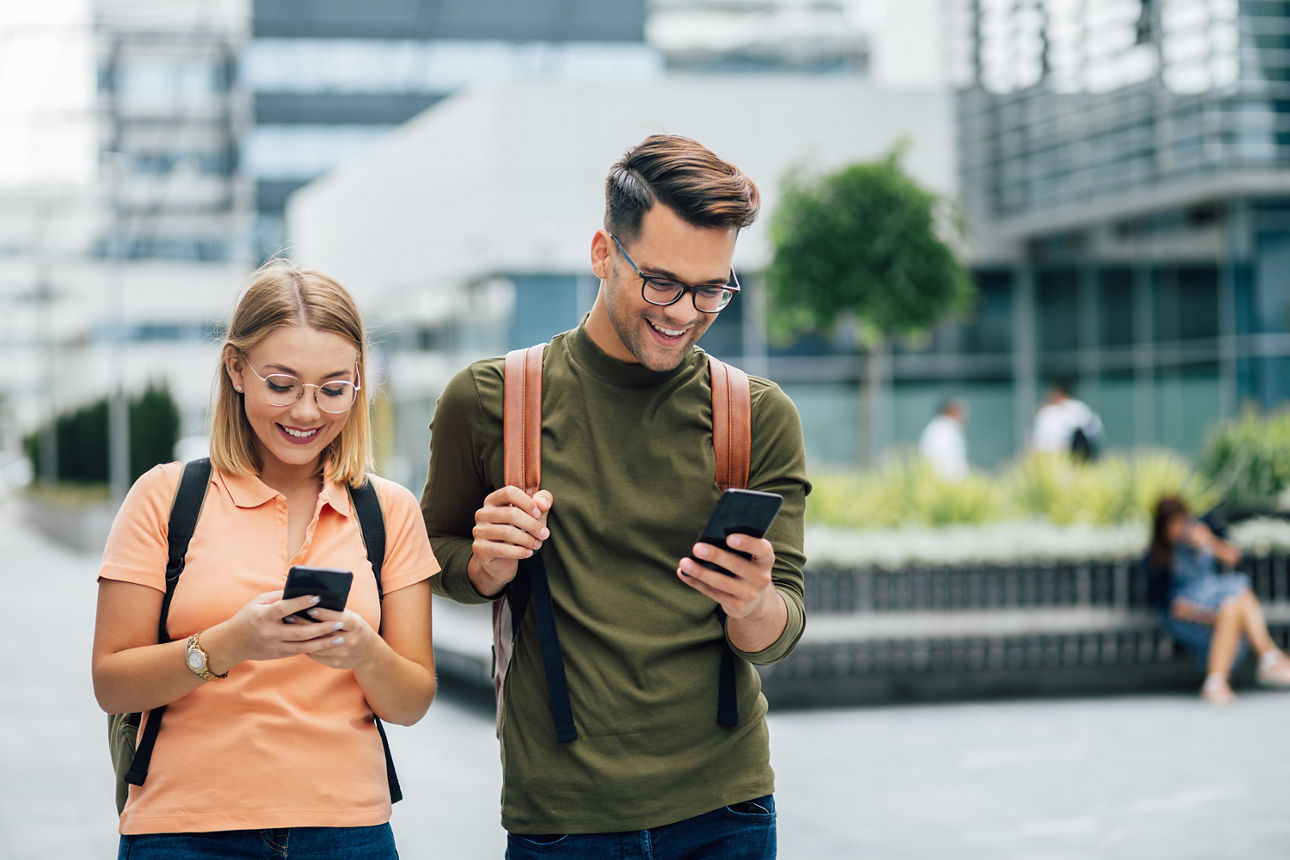 Zwei junge Menschen stehen auf der Straße und schauen auf ihr Handy