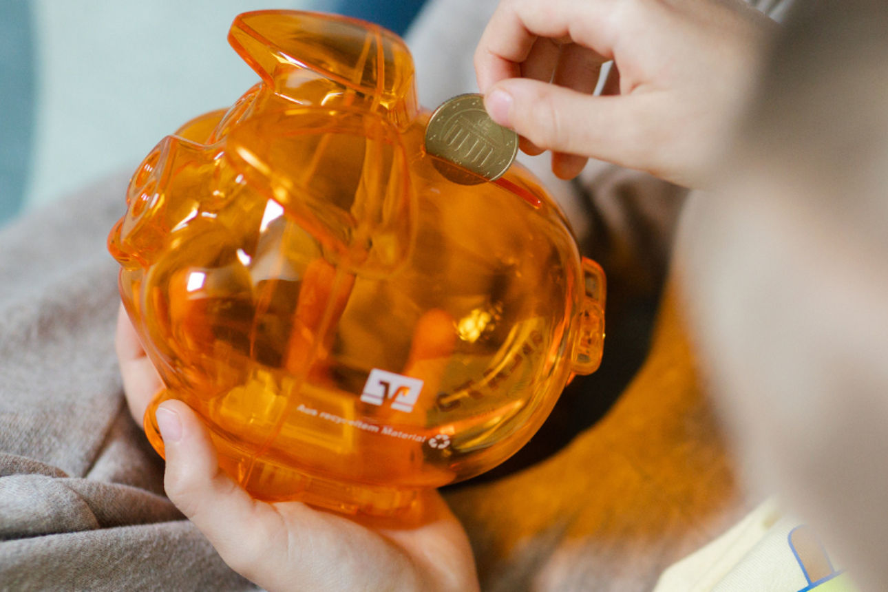Ein Kind legt Geld in ein Sparschwein.
