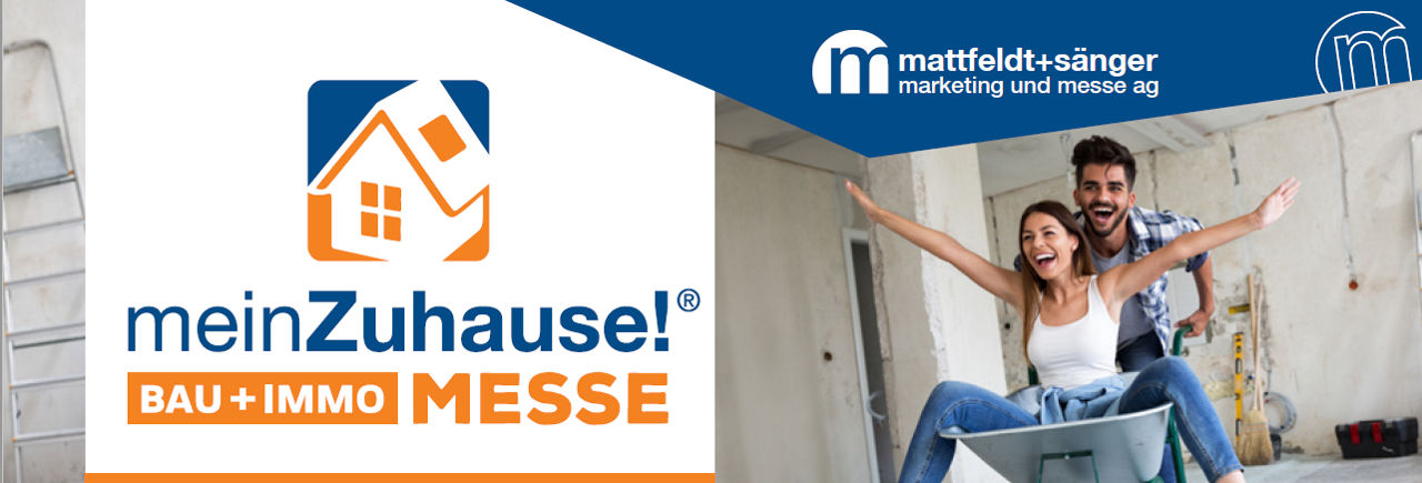 Junger Mann schiebt junge Frau im Schubkarren über eine Baustelle