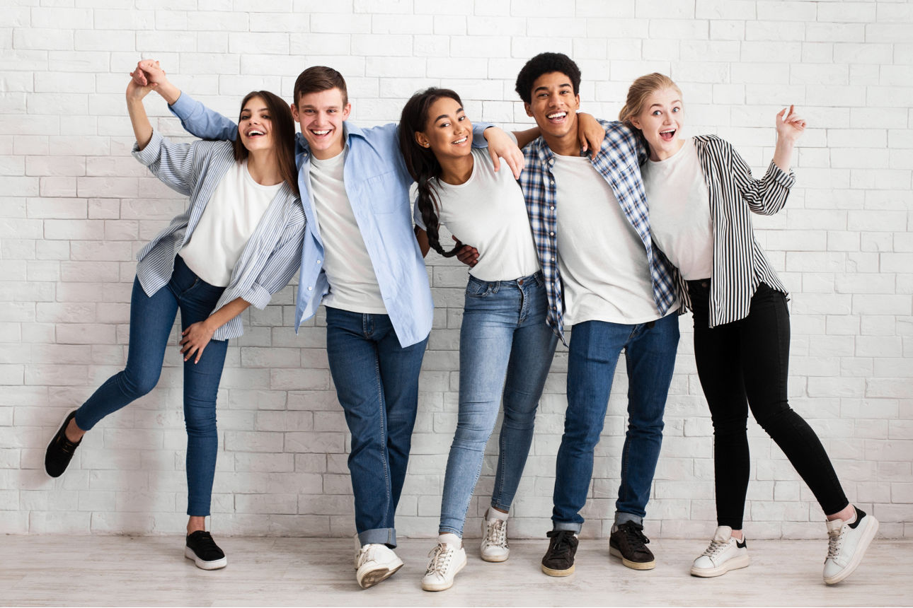 Fünf junge Leute stehen vor einer Wand und freuen sich