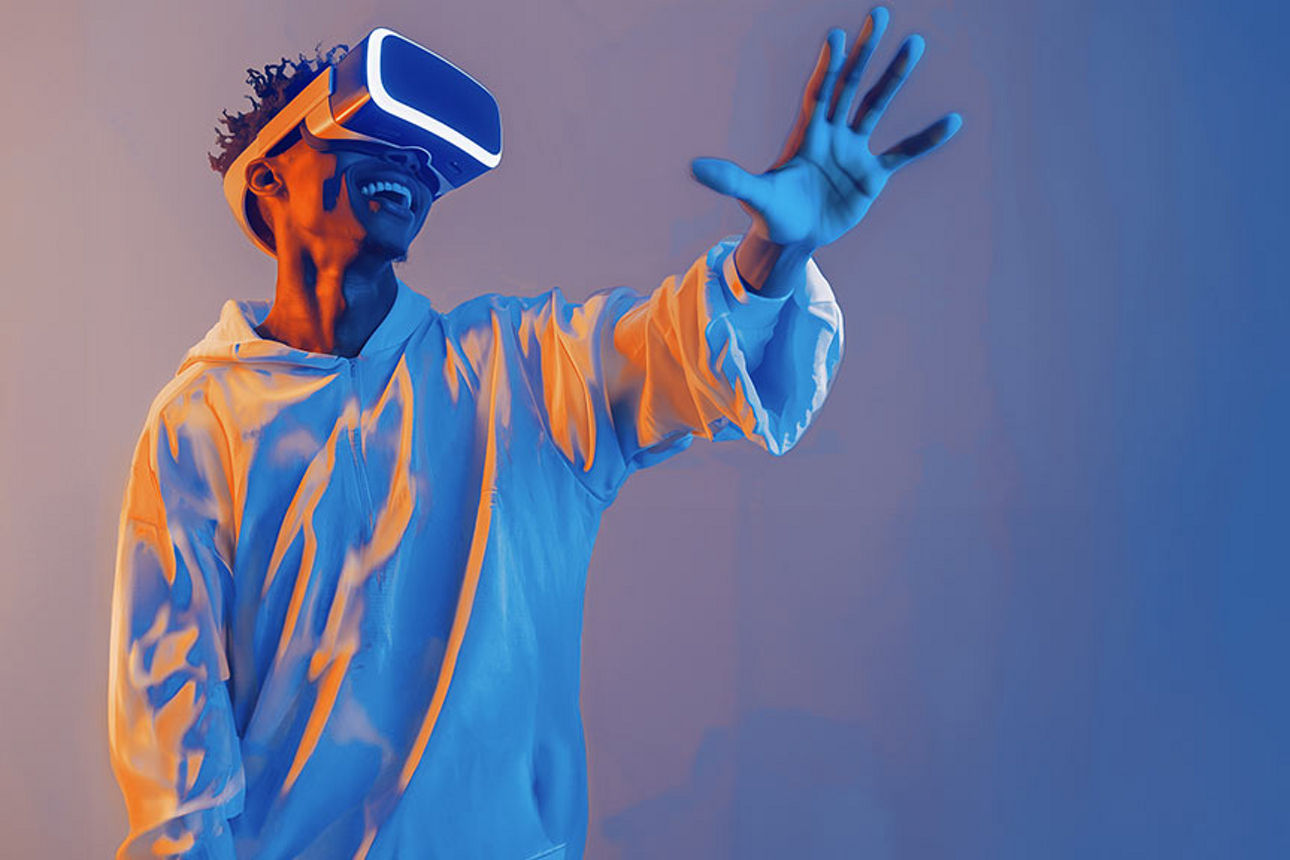 Mann steht mit VR Brille und hält lachend seine linke Hand hoch
