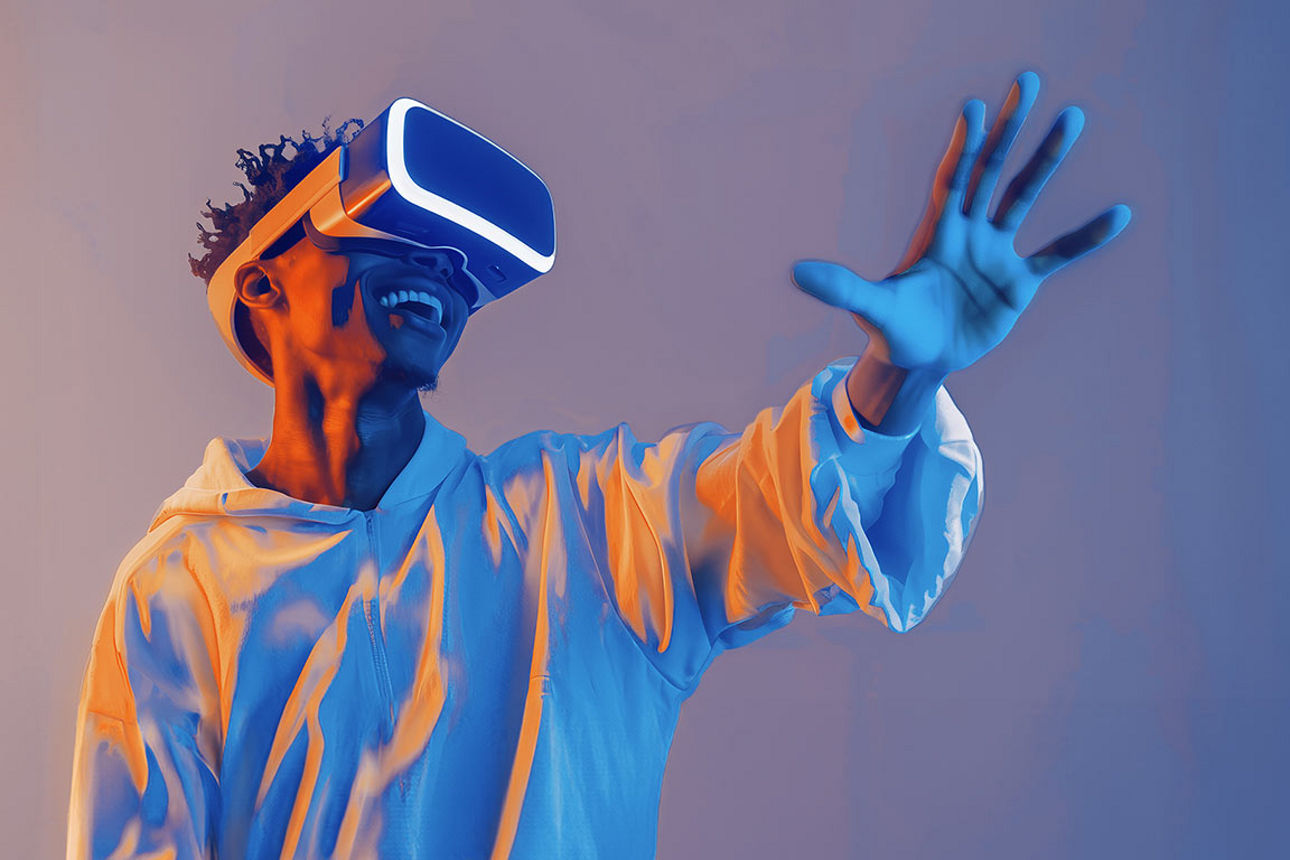 Ein junger Mann mit VR-Brille hält seine Hand nach vorne ausgestreckt und lächelt