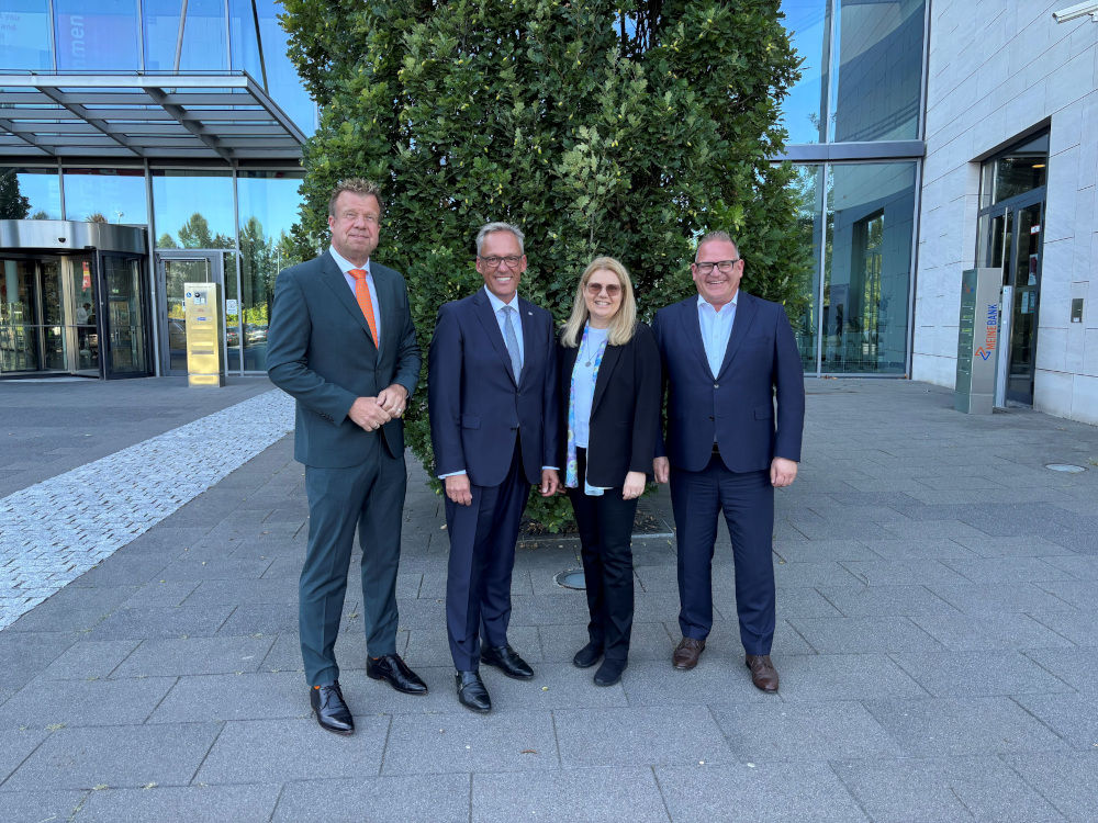 Abbildung zeigt die Vorstandsmitglieder der beiden Banken vor dem Geschäftsgebäude