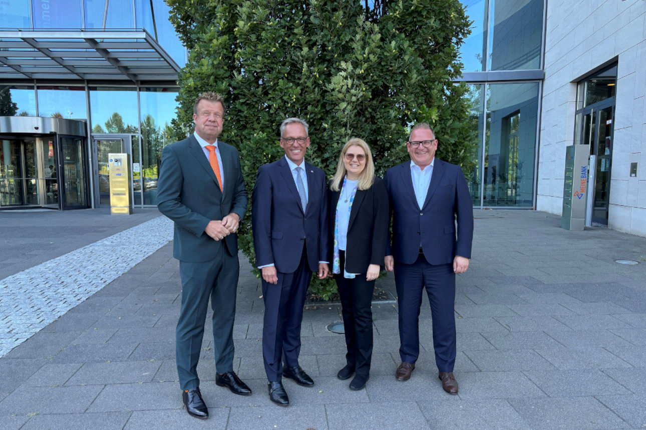 Abbildung zeigt die Vorstandsmitglieder der beiden Banken vor dem Geschäftsgebäude
