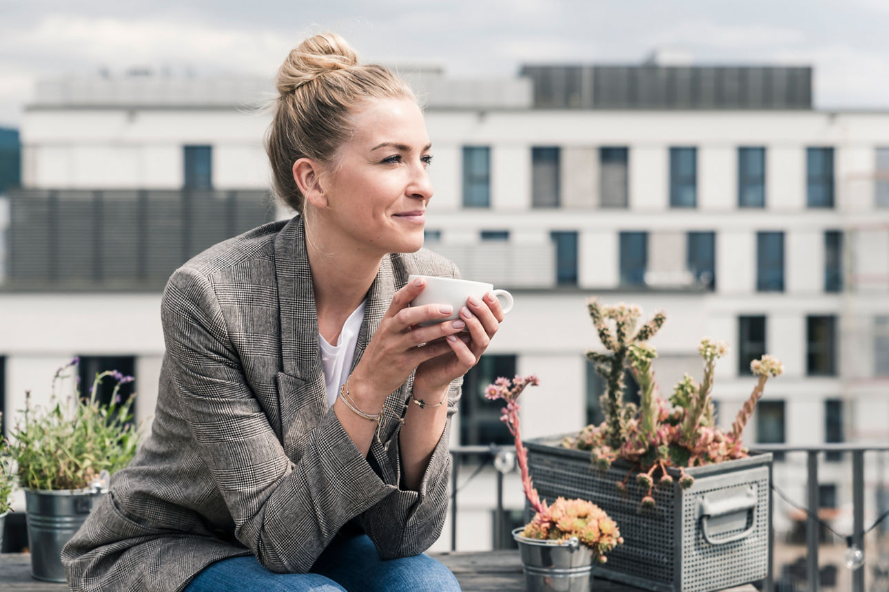Abbildung einer Dame, die gerade auf der Dachterrasse ihren Tee genießt.