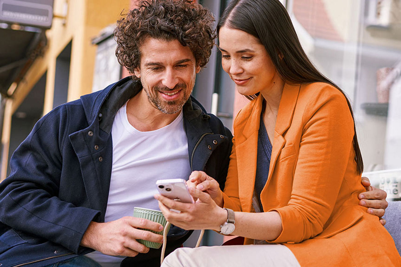 Zwei Personen schauen auf ein Handy