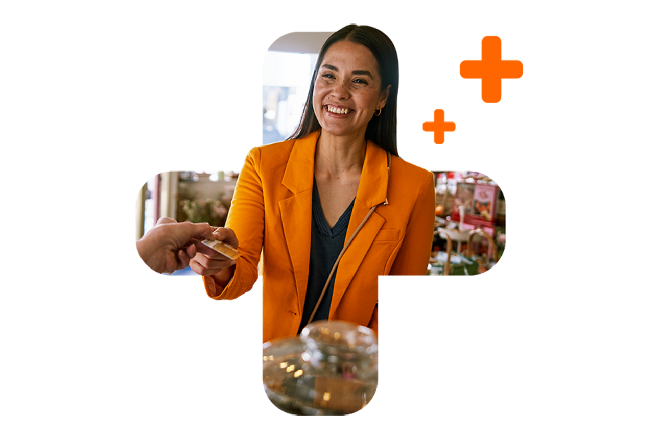 dunkehaarige Frau in orangenem Blazer, die lachend mit girocard bezahlt