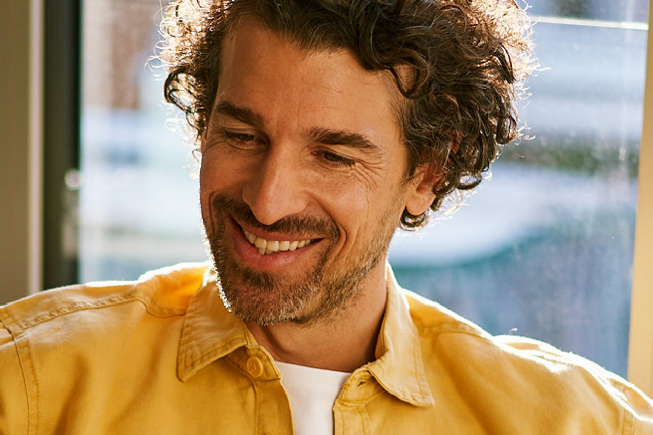 Ein junger Mann schaut auf sein Smartphone und lächelt. 