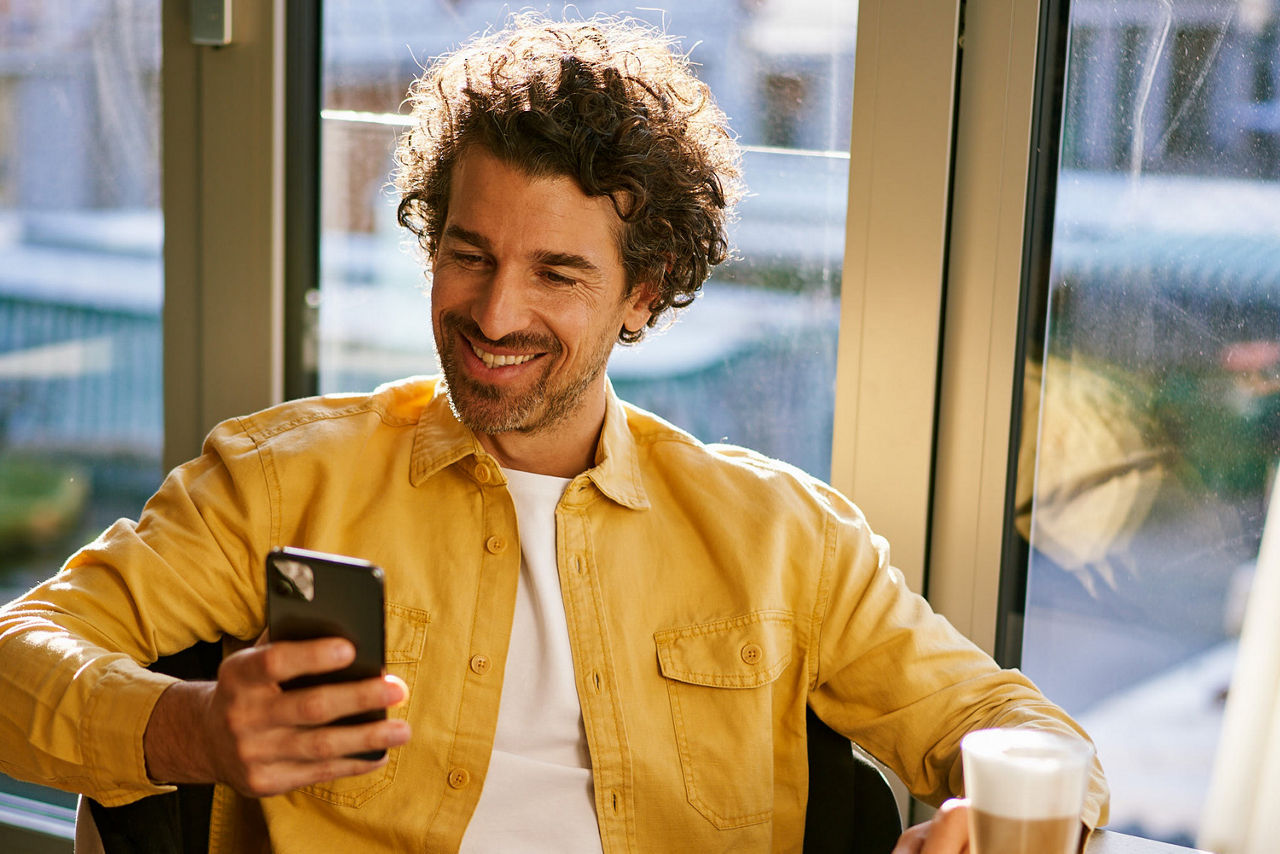 Mann schaut auf sein Handy und lächelt