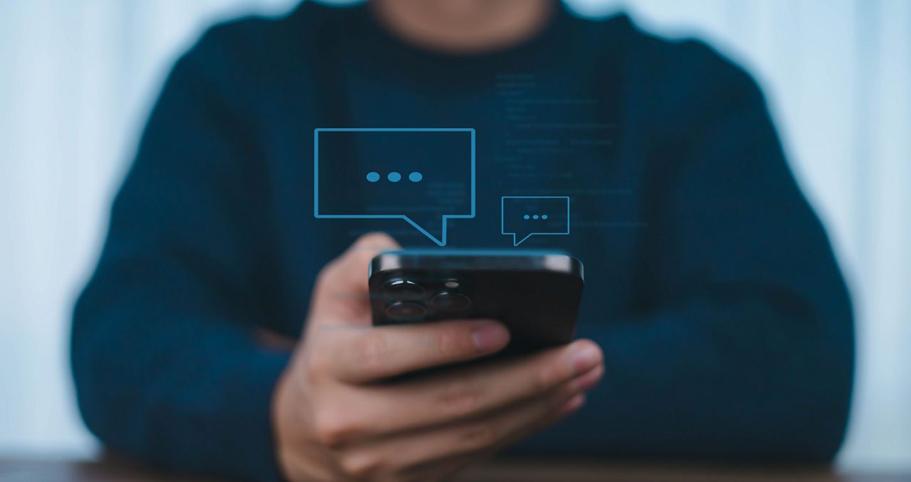 Mensch hält Smartphone in Händen - symbolisiert Betrug via Messenger