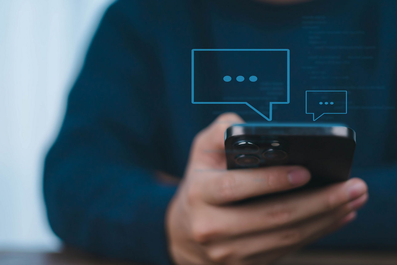 Mensch hält Smartphone in Händen - symbolisiert Betrug via Messenger