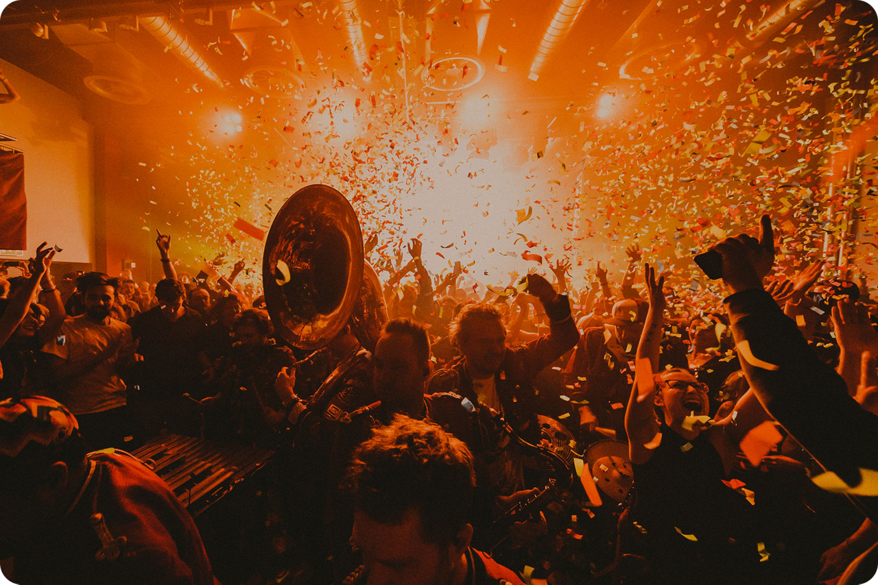 Konzertpublikum feiert in Konfettiregen vor einer Live-Band.