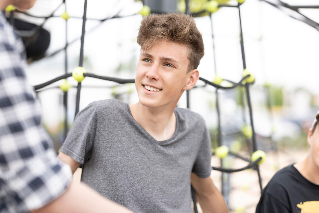 Ein kleiner Junge der sich an ein Klettergerüst lehnt.
