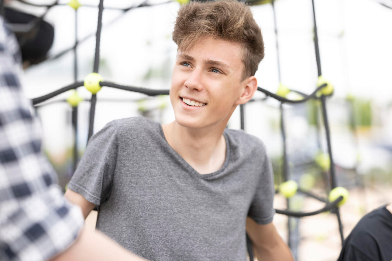 Ein kleiner Junge der sich an ein Klettergerüst lehnt.