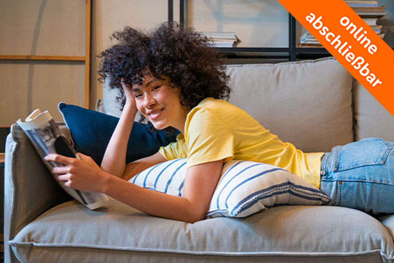 Eine junge Frau liegt auf einem Sofa und lächelt in die Kamera.