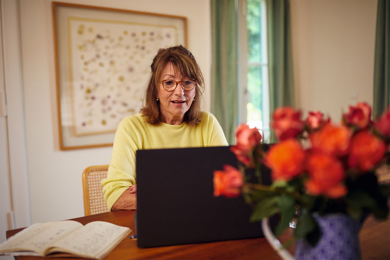 Frau sitzt mit Laptop am Tisch und arbeitet