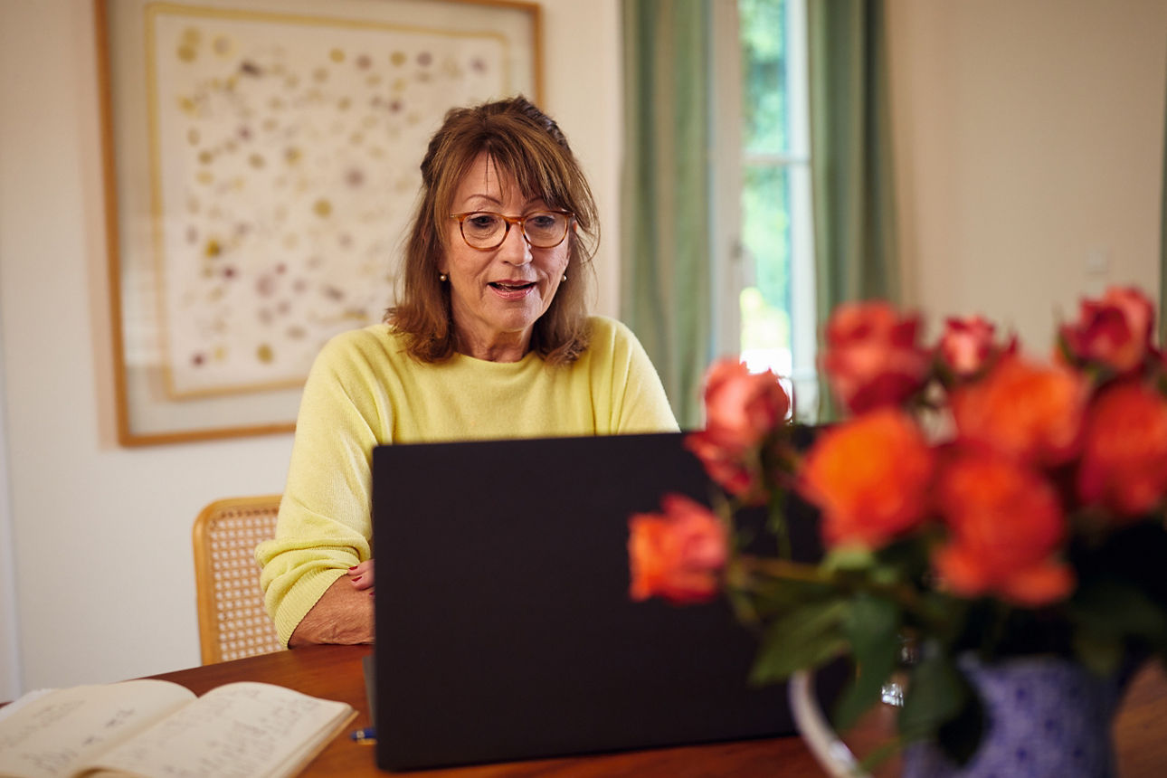 Frau sitzt mit Laptop am Tisch und arbeitet