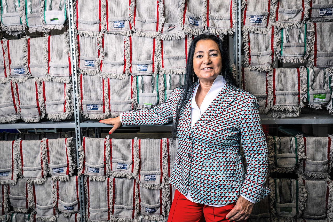 Eine Frau steht vor einem großen Regal und lächelt