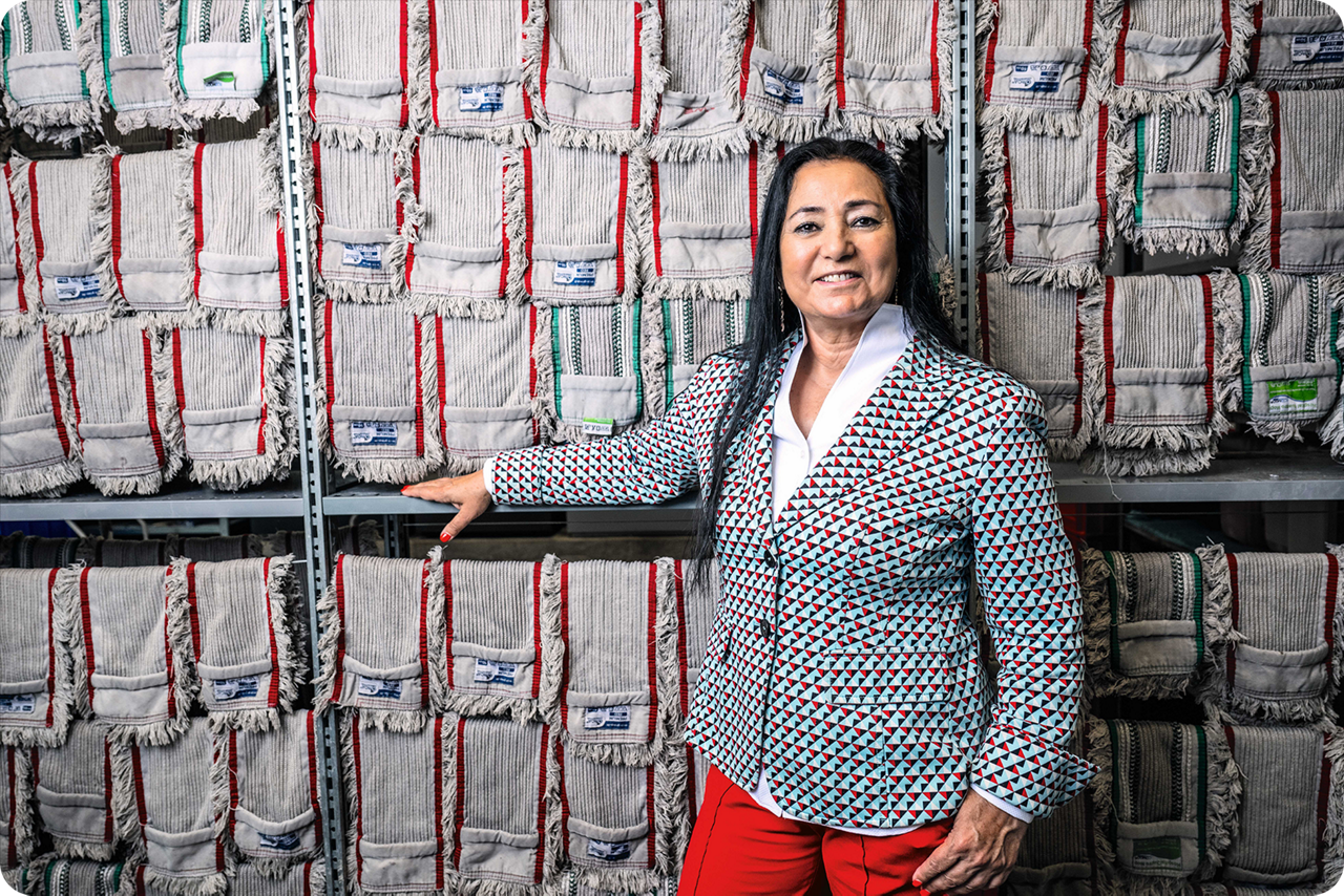 Eine Frau steht vor einem großen Regal und lächelt