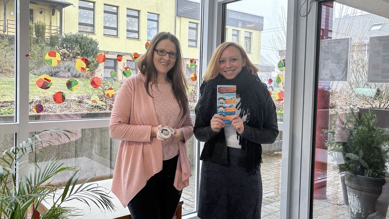 Stellvertretende Kindergartenleiterin in Anhausen nimmt Milchzahndosen und Flyer von Jennifer Einolf entgegen