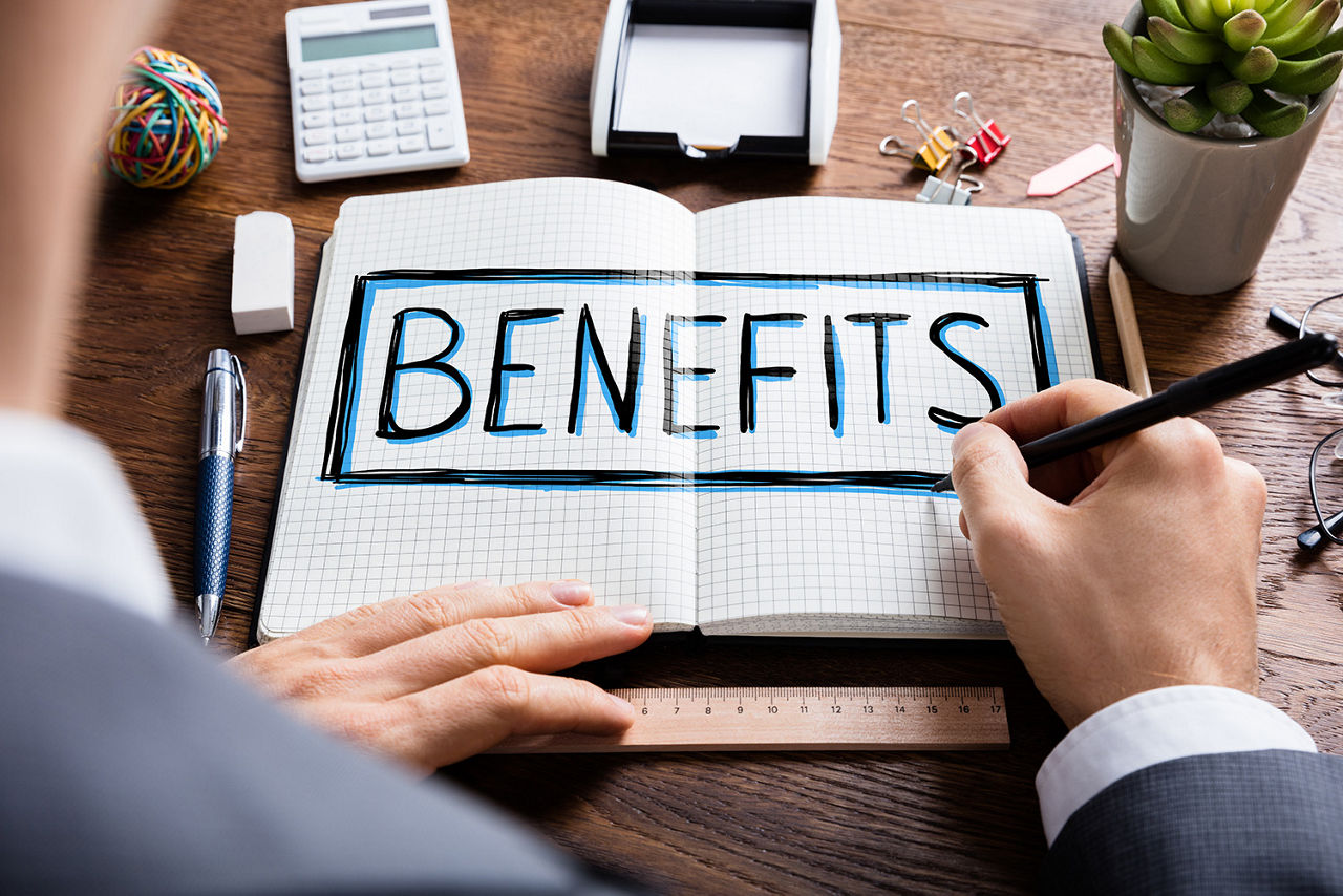 Geschäftsmann schreibt in ein Notizbuch das Wort "Benefits".