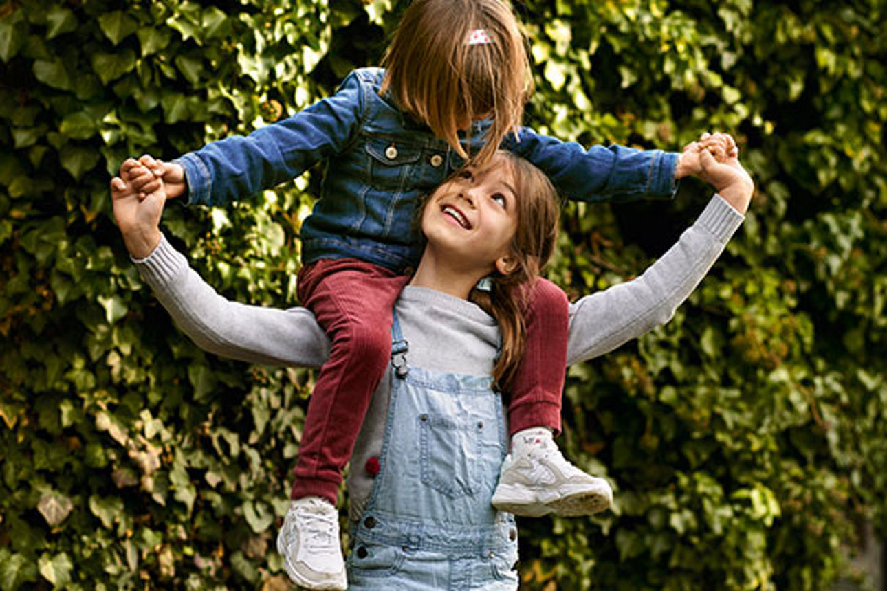 Ein Kind trägt ein anderes Kind auf den Schultern