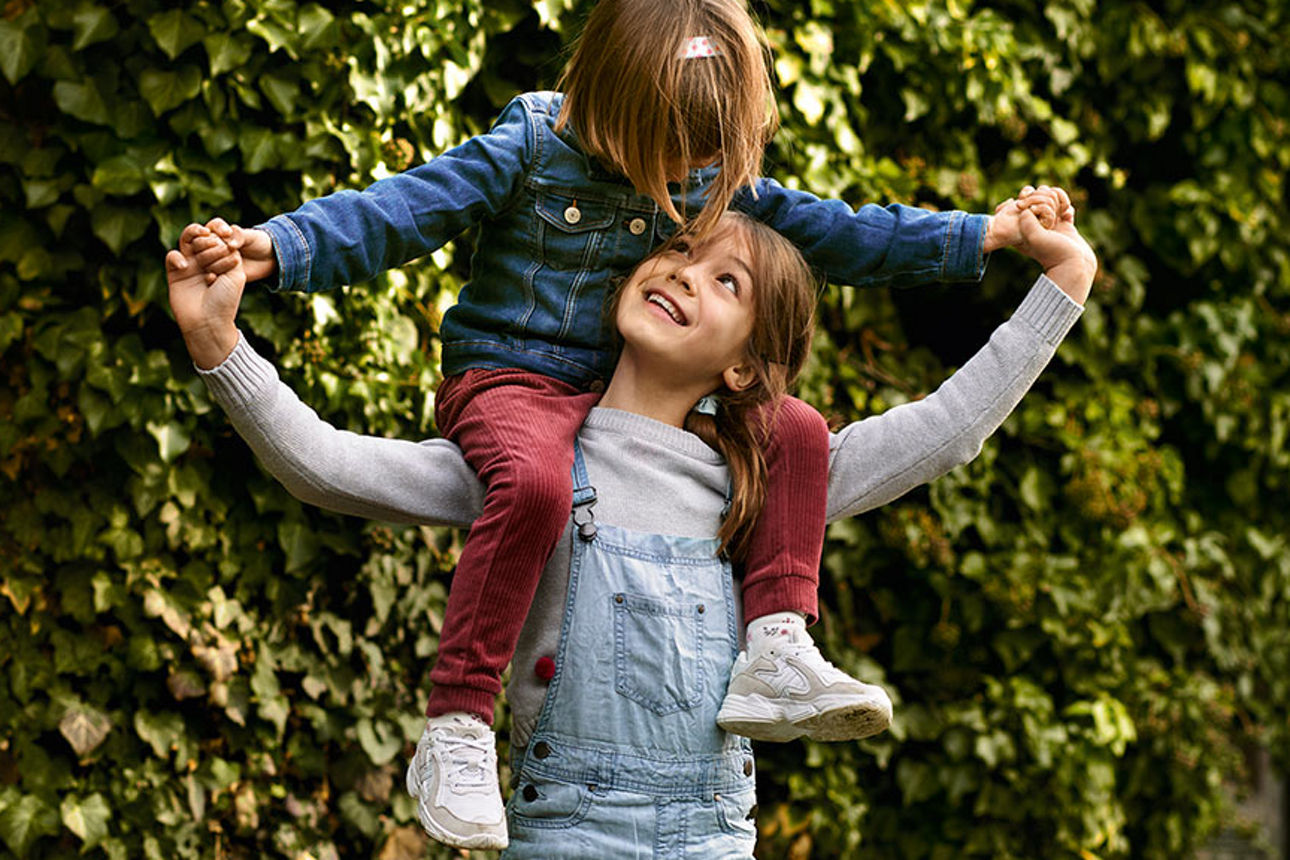 Ein Kind ist bei einem größeren Kind auf den Schultern