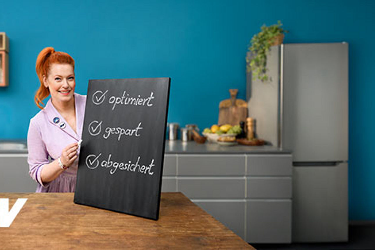 Enie van de Meiklokjes hält ein Schild mit Vorteilen des Versicherungs-Checks
