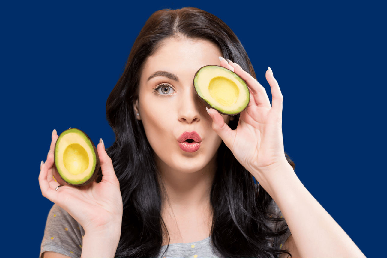 Frau mit einer halbierten Avocado vor dem Auge und eine in der Hand.