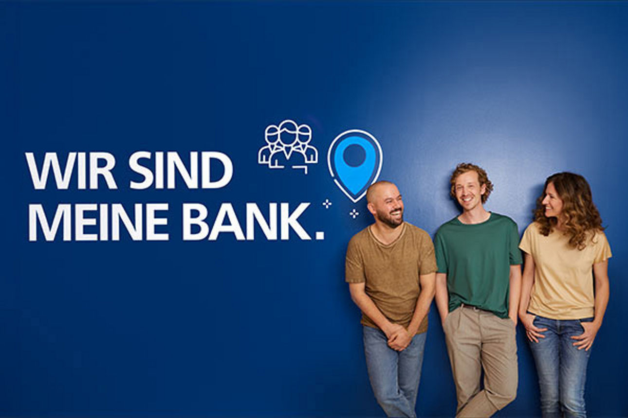 Drei Personen stehen vor einer blauen Wand mit der Aufschrift "Wir sind meine Bank"