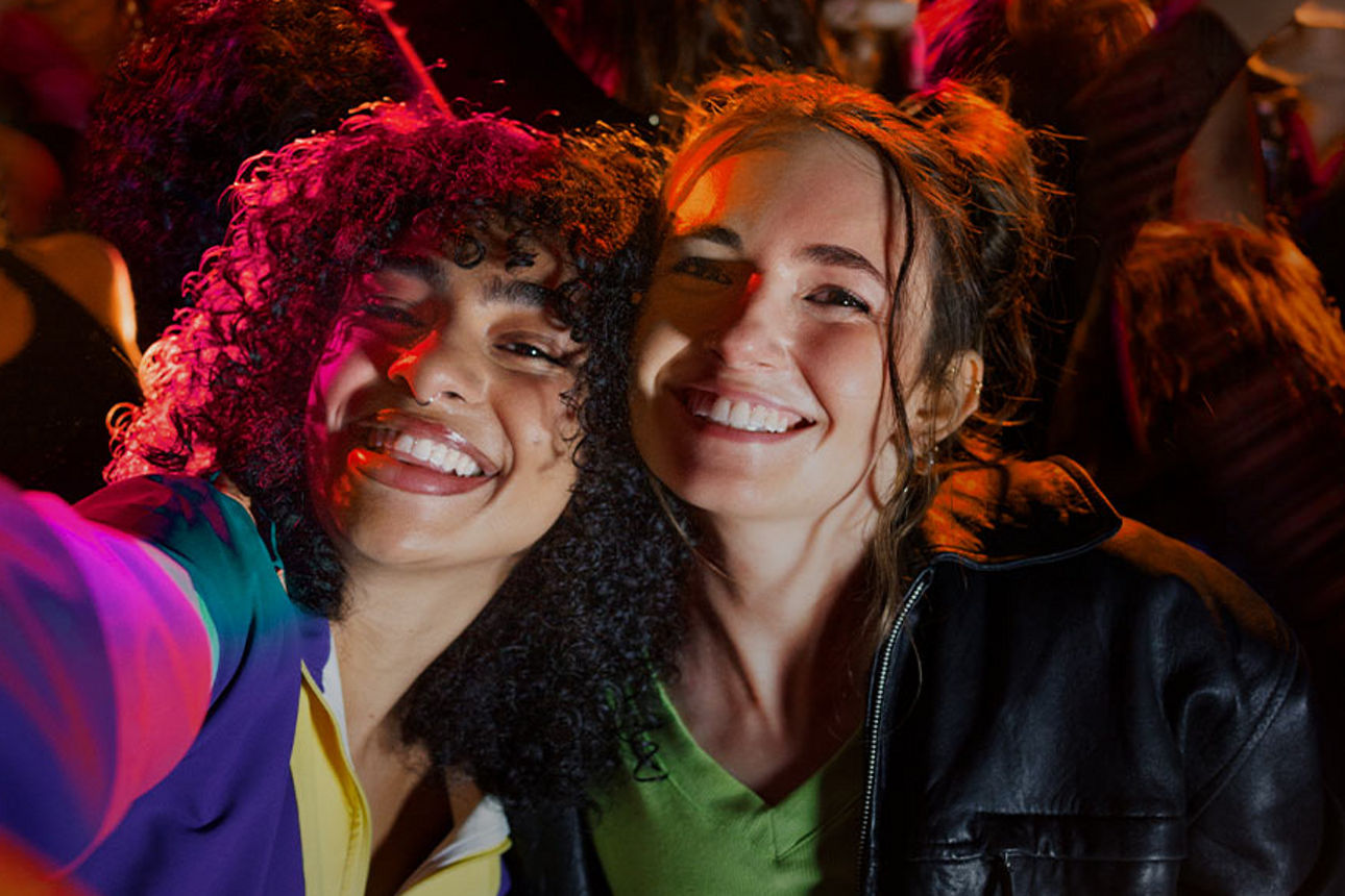 Zwei Freundinnen sind gemeinsam auf einer Party und machen ein Selfie. 