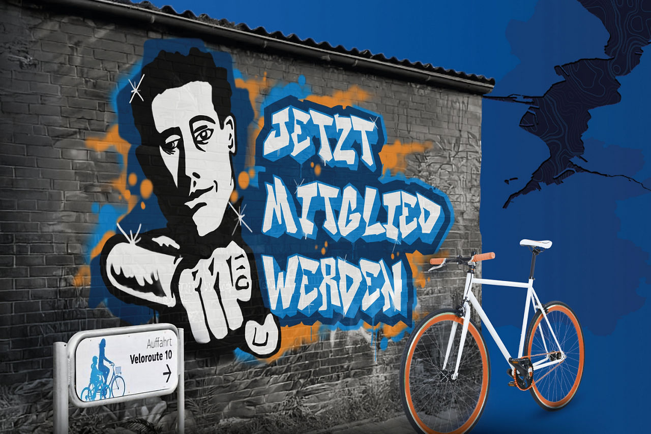 Fahrrad vor einer Wand aus Ziegelsteinen mit einem Graffiti Schriftzug "Jetzt Mitglied werden"