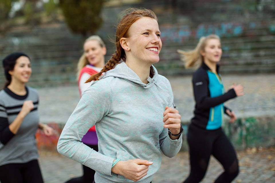 Vier Frauen laufen gemeinsam und lachen.