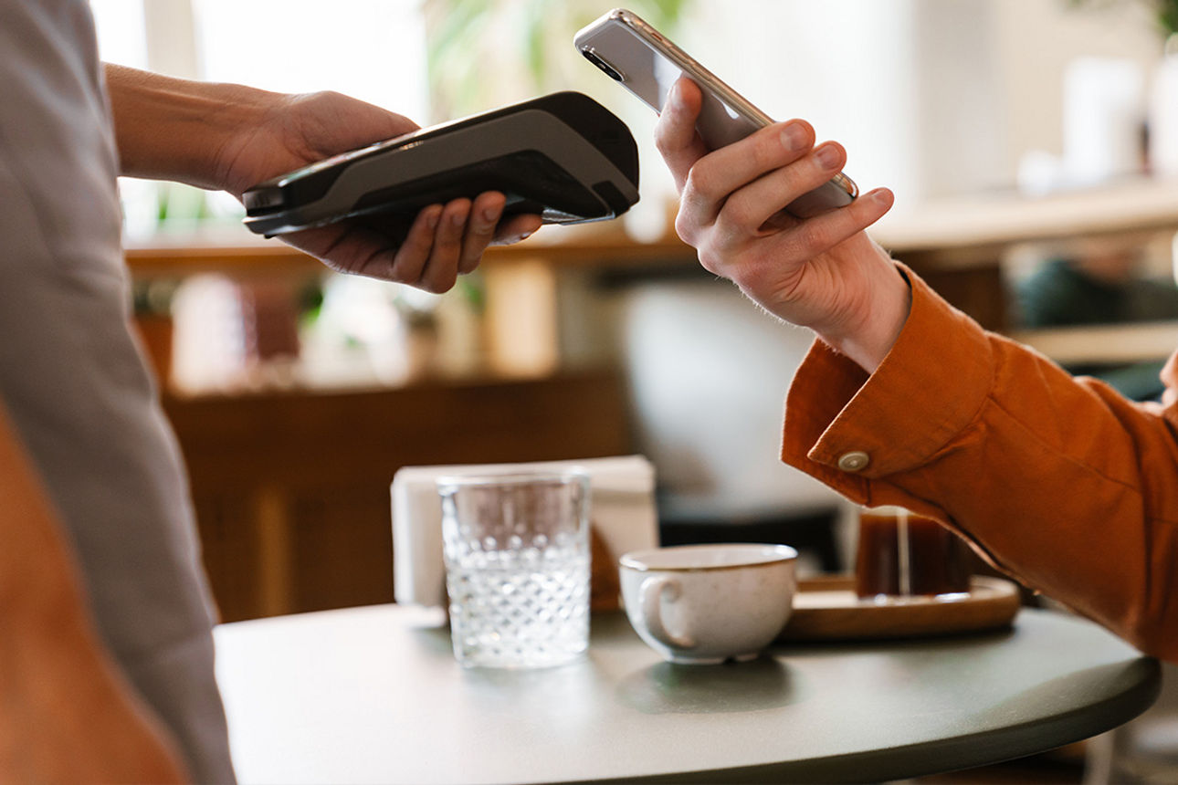 Person mit Handy beim Bezahlen