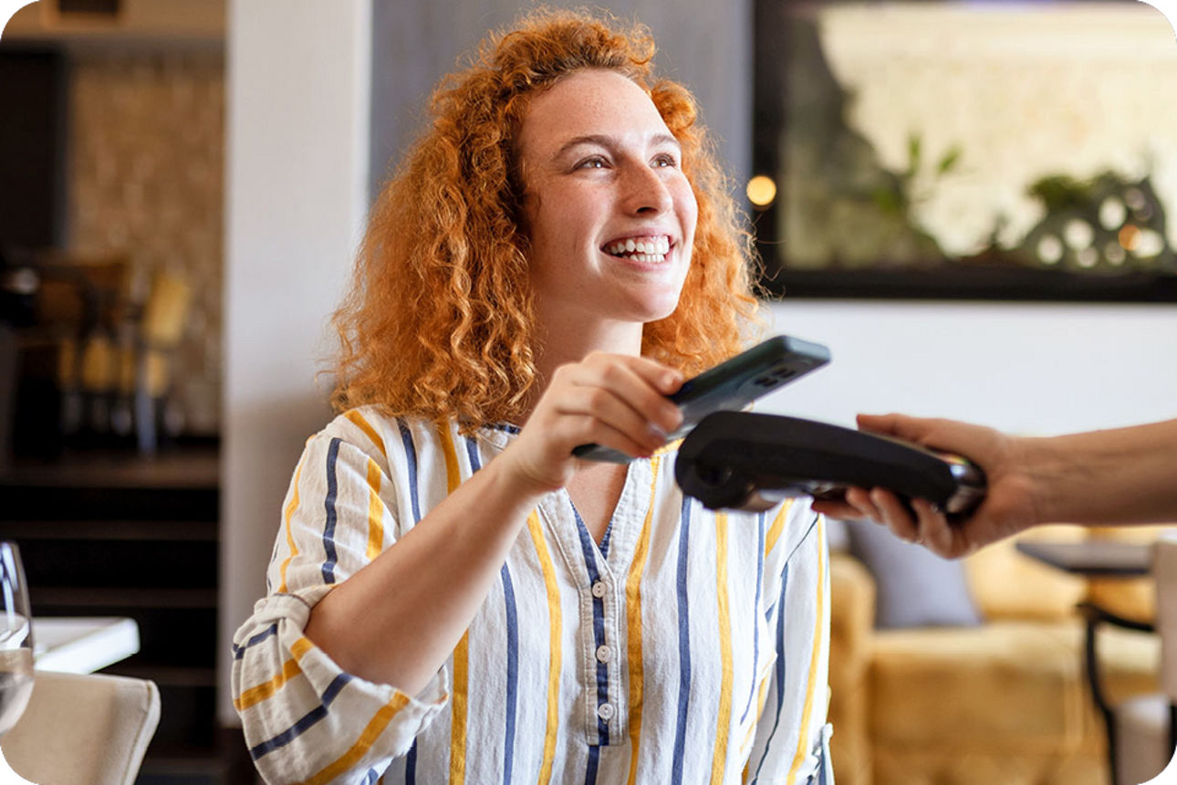 Eine junge Frau bezahlt im Restaurant mit dem Smartphone