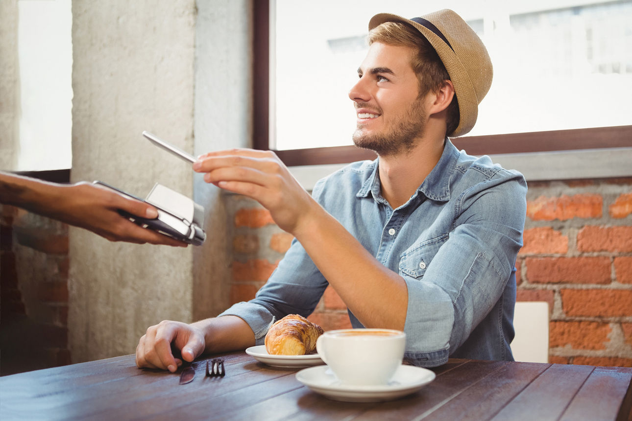 Mann bezahlt im Café mit dem Smartphone